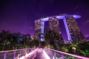 Vista icónica do Marina Bay Sands, o emblemático hotel de Singapura com a sua piscina infinita no topo, a dominar a baía com uma arquitetura futurista.