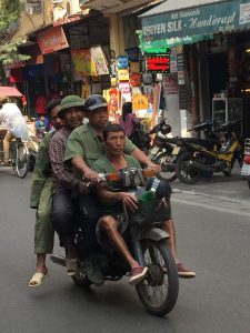 Quatro pessoas a andar numa mota nas ruas movimentadas do Vietname, uma das curiosidades do Vietname