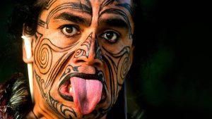 Indígena Maori - povo nativo da Nova Zelândia - expressando sua cultura através de gestos faciais e tatuagens.